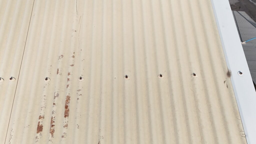 Traces de corrosion sur une toiture en tôle ondulée en acier laqué, exposée aux conditions climatiques de La Réunion