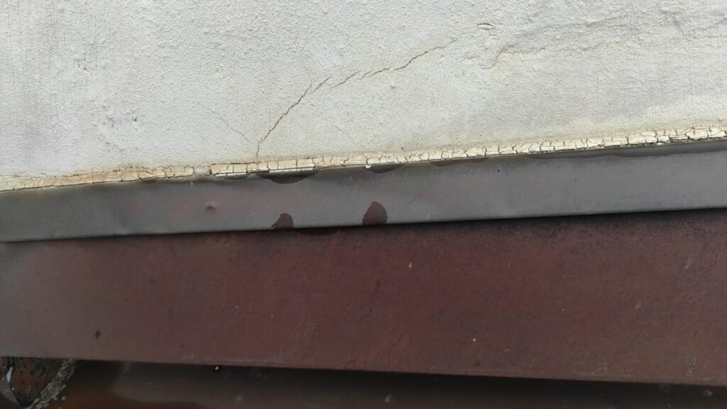 Détérioration avancée du joint silicone au-dessus de la bande à rabattre, créant un risque d'infiltration d'eau.